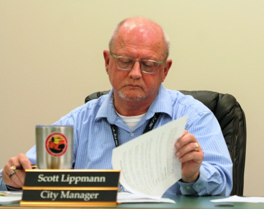 City Manager Scott Lippmann reads through his contract as council members discuss its contents.