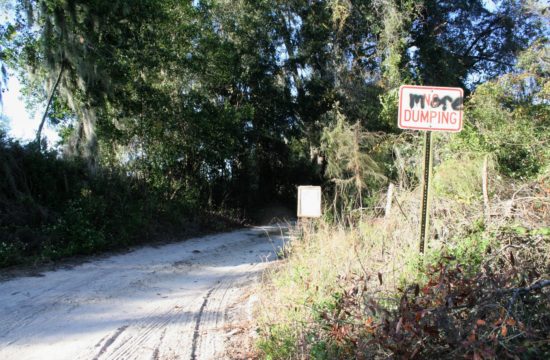 An anonymous person painted the word "more" over a county no dumping sign at the entrance to the narrowest part of the NW 40th Ave. When the road was open, only one vehicle at a time could drive on this section. There was no place to turnaround if two vehicles met.