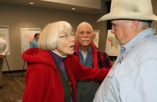 Chiefland resident Renate Cannon talks to County Commissioner Mike Joyner about the toll road as her husband Barney listens. Loud background noise from the crowd made it difficult to hear.