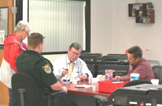 : The Levy County Canvassing Board reviews ballots Tuesday night as Deputy William Hunter watches. Canvassing board members are County Commissioner Lilly Rooks, County Judge James T. Browning and County Commission Chairman Matt Brooks. Browning chairs the canvassing board.