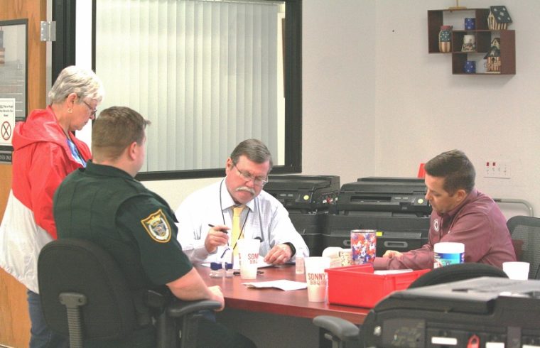 : The Levy County Canvassing Board reviews ballots Tuesday night as Deputy William Hunter watches. Canvassing board members are County Commissioner Lilly Rooks, County Judge James T. Browning and County Commission Chairman Matt Brooks. Browning chairs the canvassing board.