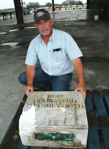 School Board member Brad Etheridge kneels behind a marble block engraved with the year 1939 and the words, "Dedicated To Our Youth." The time capsule is the rectangular copper box in front. The box is a bit weathered from the passage of 81 years.
