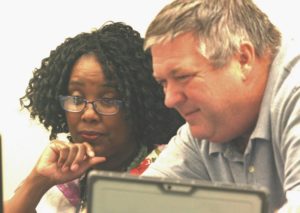 Information Technology expert Aaron Mills works with City Clerk Latricia Wright during the council meeting to work out a kink in the computer system. Mills has engineered a sound system for the city council that allows the audience to hear the board clearly. Prior to his involvement, noise from the air conditioning and heating system drowned out the voices of the council.