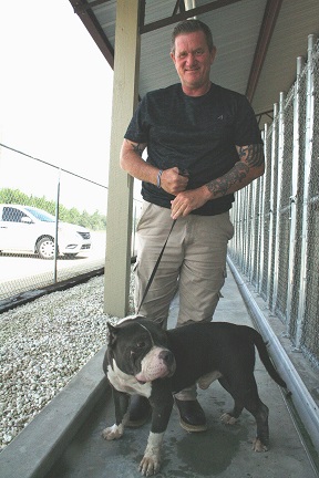 Rex the bulldog, showing off his most photogenic side, poses with Animal Services Officer Nathan Mercer.