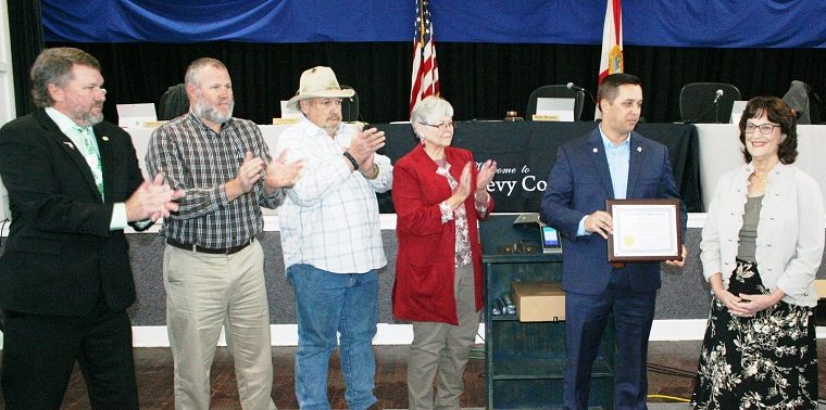 Levy County Commissioners John Meeks, Rock Meeks, Mike Joyner and Lilly Rooks applaud retiring Levy County Health Department Director Barbara Locke as Commission Chairman Matt Brooks presents her with a plaque recognizing 44 years of service to the county.