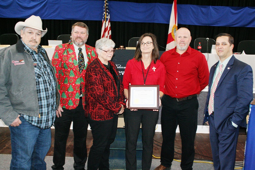 Levy County Tax Collector stands with County Commissioners Mike Joyner, John Meeks, Lilly Rooks, Rock Meeks, and Matt Brooks Tuesday after accepting a certificate plaque honoring her for more than three decades of public service.