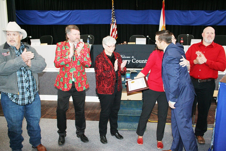 Tax Collector Linda Fugate gets a farewell hug from County Commission Chairman Matt Brooks and commissioners Mike Joyner, John Meeks, Lilly Rooks and Rock Meeks applaud her 35 years of public service to Levy County.