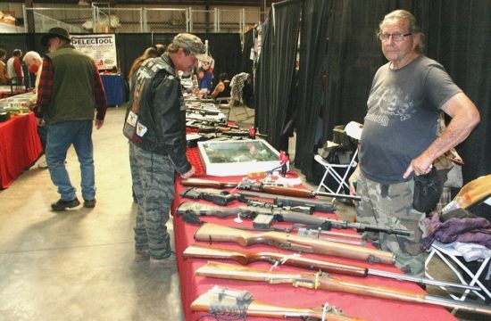 One of the many vendors at the Williston Gun Show displays an assortment of weapons, including antique collectible guns, as customers browse his offerings.