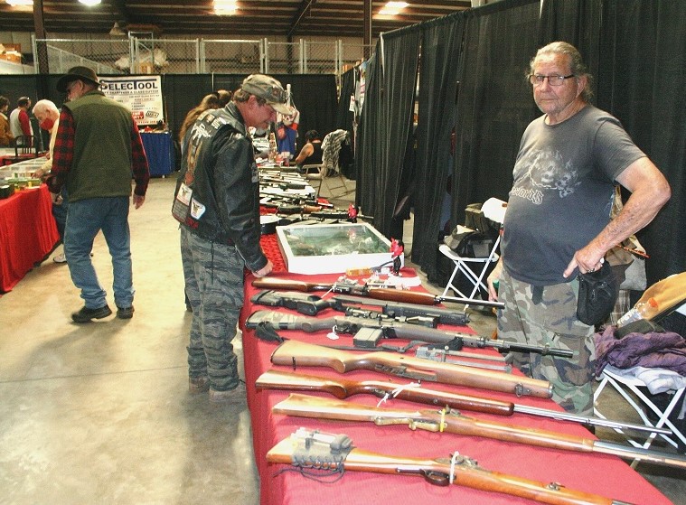 One of the many vendors at the Williston Gun Show displays an assortment of weapons, including antique collectible guns, as customers browse his offerings.