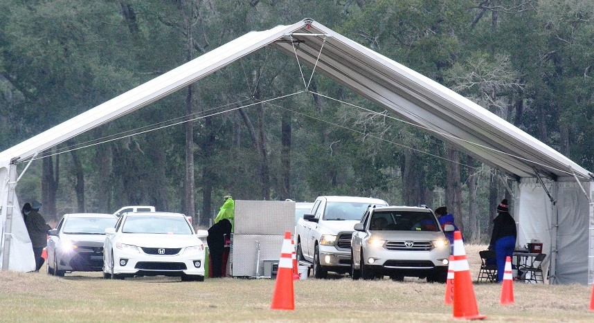 Two lines of vehicles park under the big vaccination tent. The driver and passenger sometimes received their vaccinations at the same time on opposite sides of the car or truck.