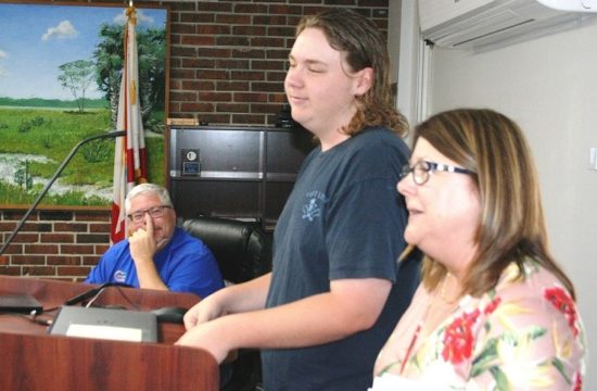 Hayden Asbell, the only high school student in Florida to pass two water and wastewater certificate courses, is introduced to the Levy County School Board and visiting guests and staff by retiring Career and Technical Education Coordinator Carol Jones-Dubois. Hayden's father, School Board Chairman Cameron Asbell, can be seen in the rear watching his son.