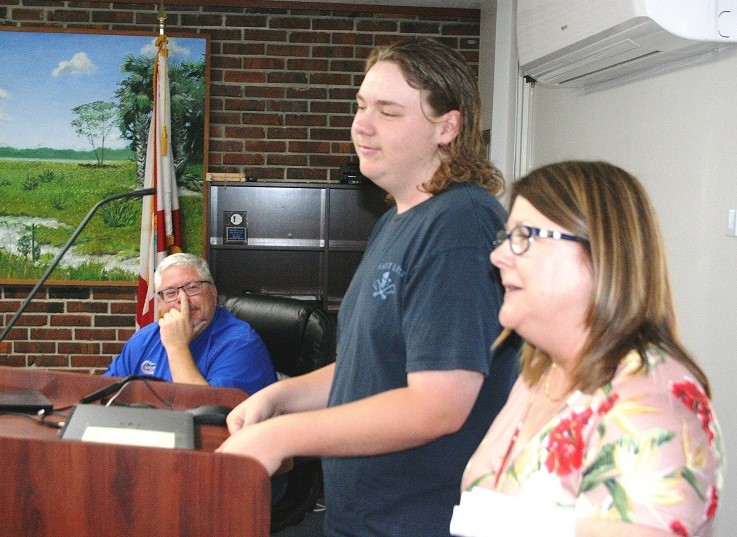 Hayden Asbell, the only high school student in Florida to pass two water and wastewater certificate courses, is introduced to the Levy County School Board and visiting guests and staff by retiring Career and Technical Education Coordinator Carol Jones-Dubois. Hayden's father, School Board Chairman Cameron Asbell, can be seen in the rear watching his son.