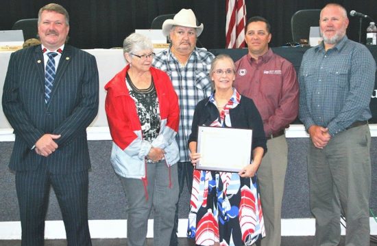 Levy County Commissioners John Meeks, Lilly Rooks, Mike Joyner, Matt Brooks, and Rock Meeks present retiring County Attorney Anne Bast Brown with a plaque expressing their appreciation for her 17 years of service.