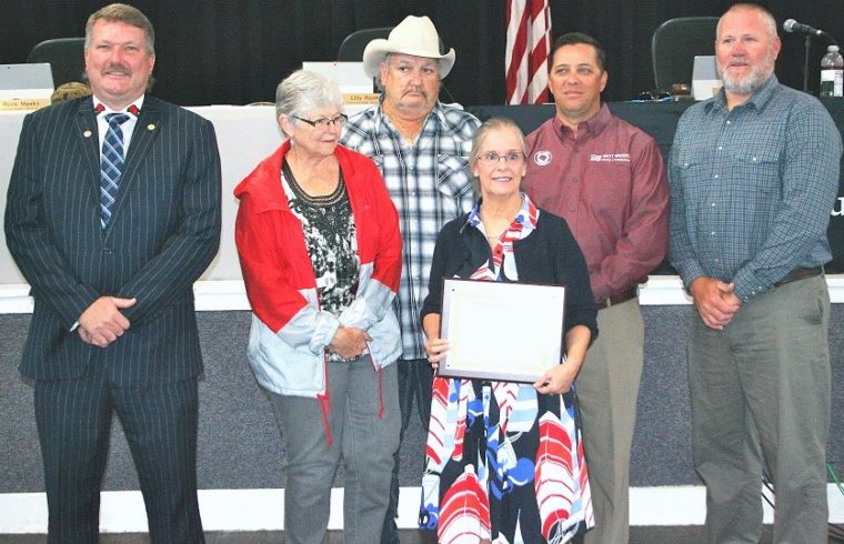 Levy County Commissioners John Meeks, Lilly Rooks, Mike Joyner, Matt Brooks, and Rock Meeks present retiring County Attorney Anne Bast Brown with a plaque expressing their appreciation for her 17 years of service.