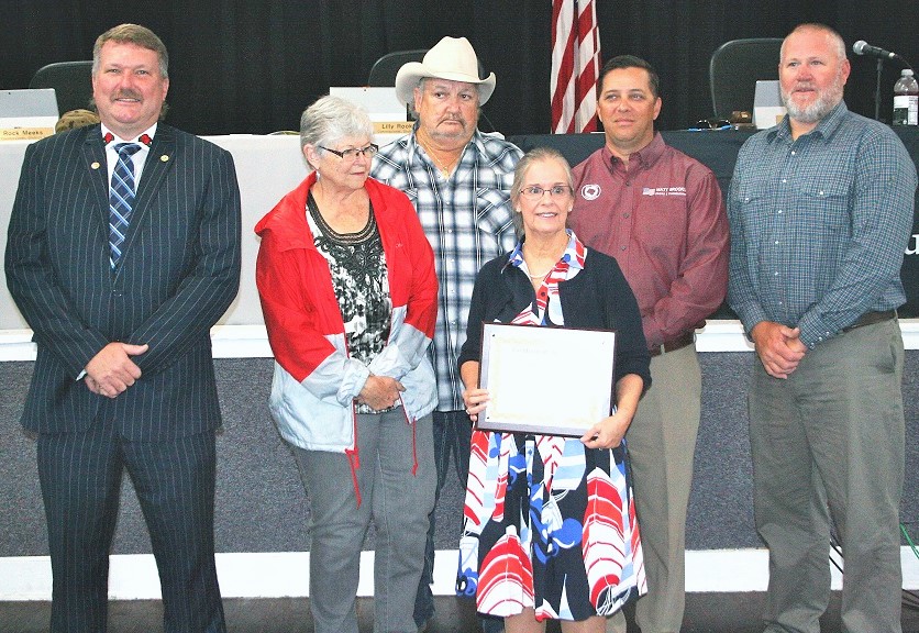 Levy County Commissioners John Meeks, Lilly Rooks, Mike Joyner, Matt Brooks, and Rock Meeks present retiring County Attorney Anne Bast Brown with a plaque expressing their appreciation for her 17 years of service.