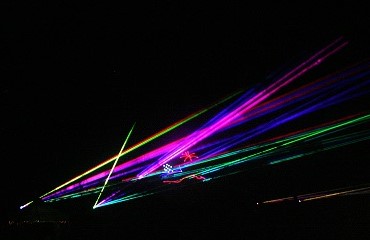 A stream of colorful laser beams lights up the air over the crowd.