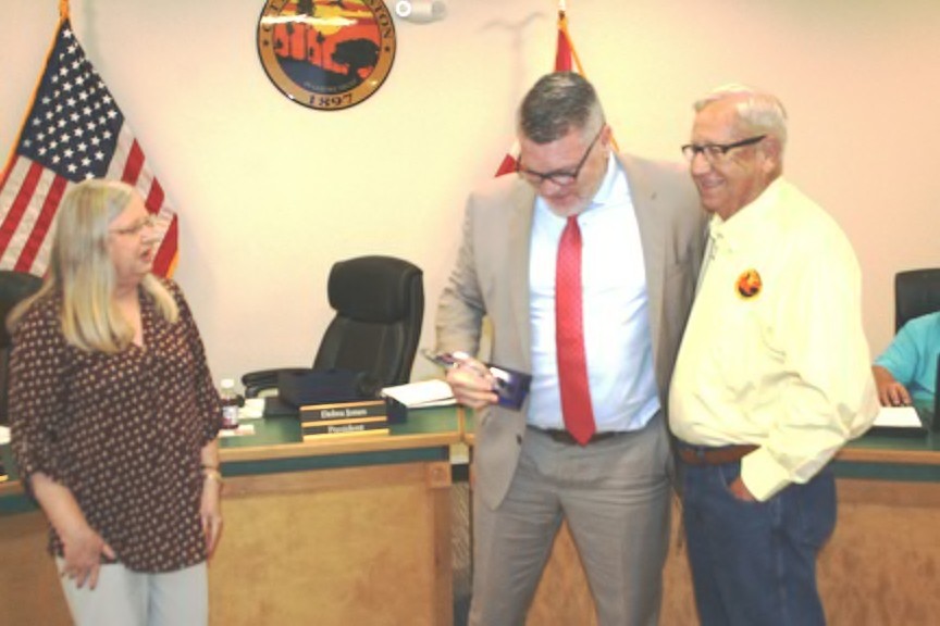 Fred Koberlein jokes with Mayor Jerry Robinson as Council President Debra Jones looks on. Koberlein is holding the desktop plaque given to him by Jones.