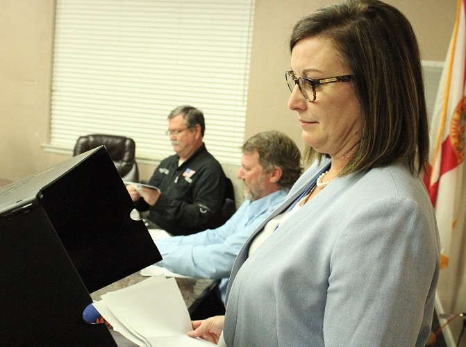 Supervisor of Elections Tammy Jones, feeds mail-in ballots into a machine that tabulates them as Canvassing Board members John Meeks, and James T. Browning work behind her.