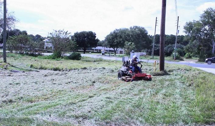 An unidentified woman completes mowing on the front portion of the hospital property.