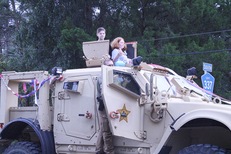 Two future law officers sit atop a Levy County Sheriff's Office armored vehicle enjoying the parade from an elevated platform.