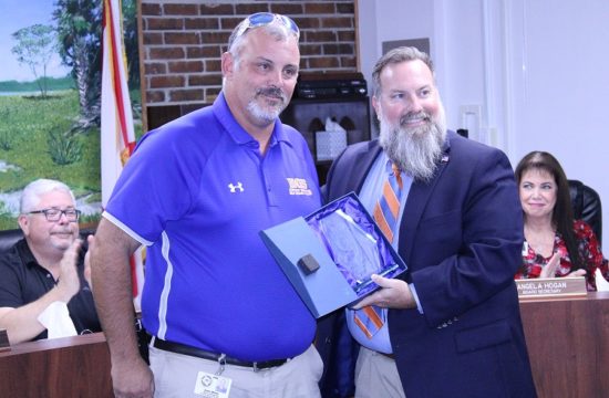 School Superintendent Chris Cowart presents Bronson Middle High School Dean John Miller with a certificate for coming to the aid of a football player from another school.
