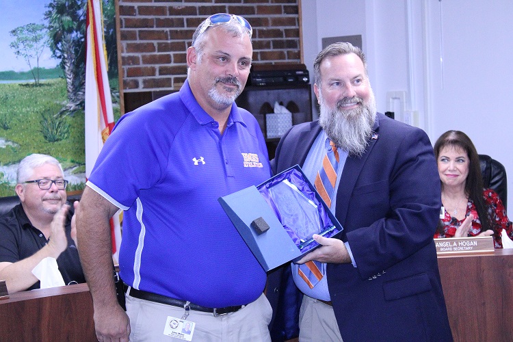 School Superintendent Chris Cowart presents Bronson Middle High School Dean John Miller with a certificate for coming to the aid of a football player from another school.