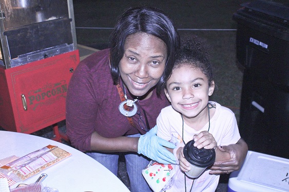 Williston City Clerk Latricia Wright and her granddaughter Adrianna Faison, 6, enjoy movie night. Wright brought hot cocoa and popcorn to Movie Night at the Park.