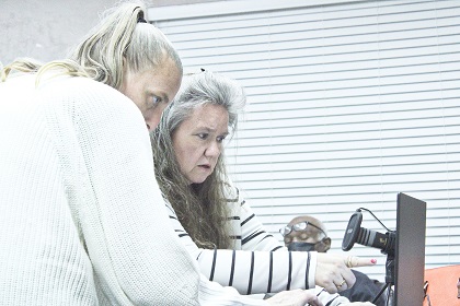 Bronson Town Manager Susan Beaudet points to the screen of a laptop as she and Deputy Clerk Wendy Maragh look for the image of Town Attorney Steven Warm. Warm attends town council meetings by internet link. His image and voice can be seen and heard through the laptop. The quality of Warm's participation has improved lately, though sometimes he still has to be prodded to respond to a council question as if he wasn't listening or couldn't hear what was stated.