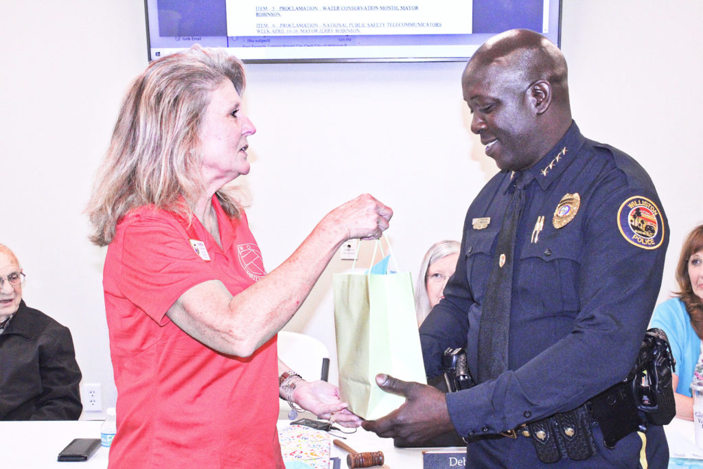 Sharon Oliphant, past state president of GFWC and a member of the Williston Woman's Club presents incoming Police Chief Mike Rolls with a coffee cup as a welcome present.
