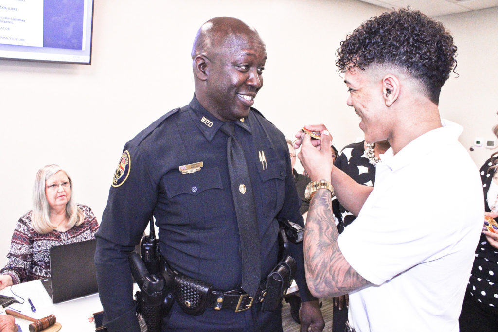 Incoming Police Chief Mike Rolls watches as his son Jaron Rolls prepares to pin the chief's badge to his uniform. Rolls reminded his son the needle was sharp. They laughed.  