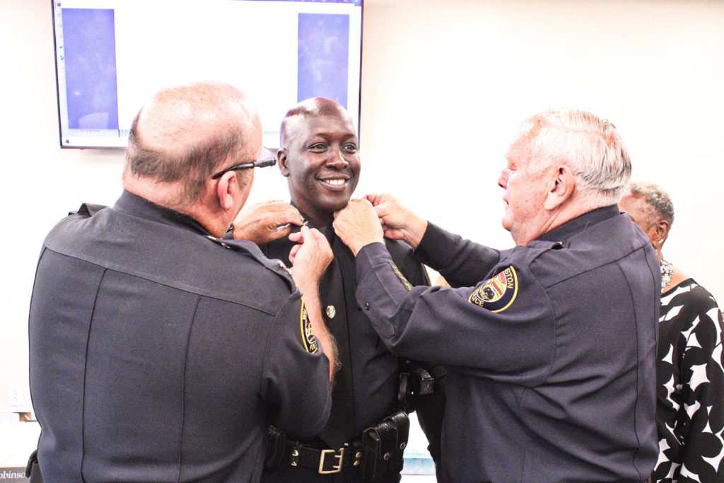 Incoming Police Chief Mike Rolls smiles as Deputy Chief Terry Bovaird and Police Chief Dennis Strow pin stars to his lapel.