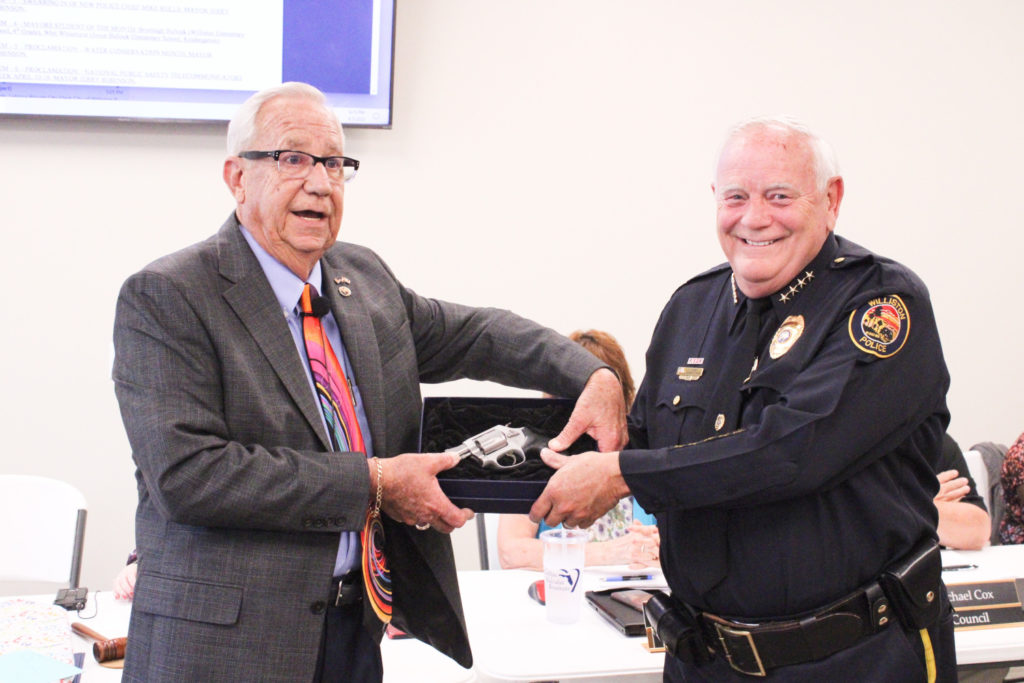 Mayor Jerry Robinson presents Chief Dennis Strow with his service weapon and draws laughter as he jokes about the chief good-naturedly.