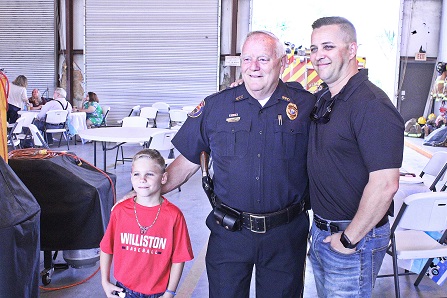 Levy County Commissioner Matt Brooks and his son Bowen pose for a photo with Police Chief Dennis Strow at the retirement party.