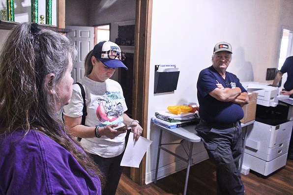 Bronson Town Manager Susan Beaudet, District 4 county commission candidate Charlene "Watson" Calvillo, and Fire Chief Dennis Russell prepare for Beautify Bronson. Calvillo is using GPS on her phone to locate the streets she was assigned to clean up. Russell has been assigned desk duty due to a foot injury and couldn't participate but was present for the initial gathering of volunteers at Town Hall.