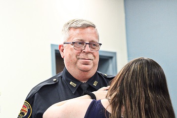 Sgt. Tim O'Hara smiles as a family member pins on the badge. His promotion to sergeant was announced at the meeting.