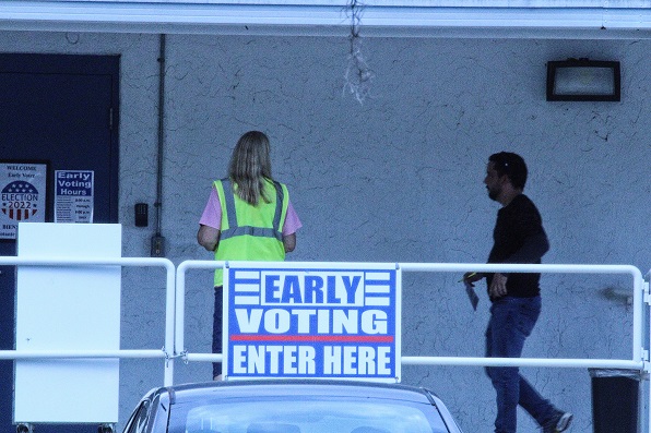 An election's office worker greets an early voter as he heads for the entrance of the polling place. The same woman tried to tell a Spotlight reporter he wasn't allowed to be close to election's office taking photos. This photo was taken with a 300 mm telephoto lens while the photographer was standing on the lawn of the First Baptist Church property. The problems resulted when the photographer walked up to ask for the name of the election's office worker. She declined to identify herself. The photographer was wearing "I voted early" sticker on his shirt. He still wasn't welcomed.