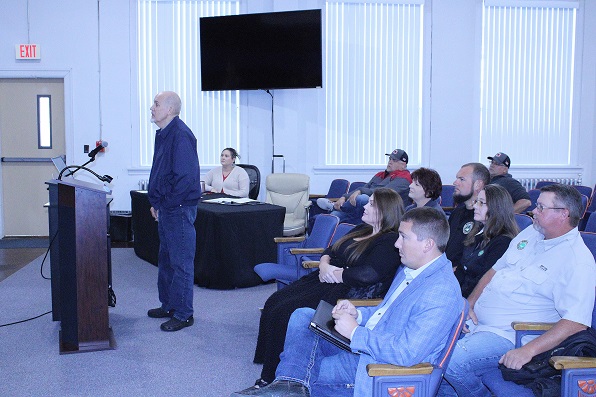 Former Interim Property Appraiser Randy Rutter speaks to the Value Adjustment Board as Black Prong Mayor Clayton Bratcher (foreground) listens to Rutter's comments with other company officials.