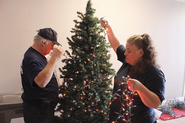 Fire Chief Dennis Russell and firefighter Cindy Waters string lights on a Christmas tree outside the current fire offices at the Dogan Cobb Municipal Building.