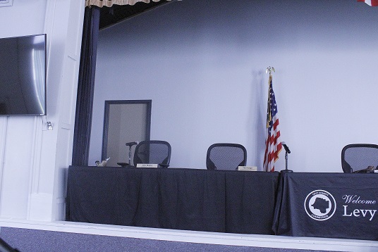 The entrance door for the room where the board ate lunch can be seen on the left behind the table, or dais, where they sit for their meetings.