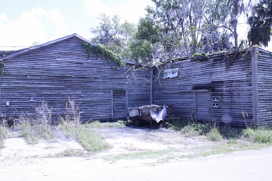 The mid-section of the Pesso's property shows foliage growing out of the roof and exterior wall boards that appear to be in bad shape.