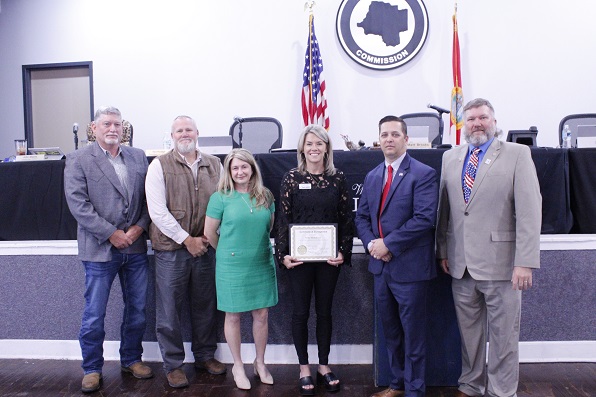 Commissioners Honor Tourism Development Director Tisha Whitehurst with a certificate for 10 years of service. She was unable to attend when the other county employees were honored at a previous board meeting. She wanted to see her son awarded his second livestock championship at the Suwannee River Fair. Shown from the left are Commissioners Tim Hodge, Rock Meeks, Desiree Mills, Whitehurst, Commission Chairman Matt Brooks and Commissioner John Meeks.