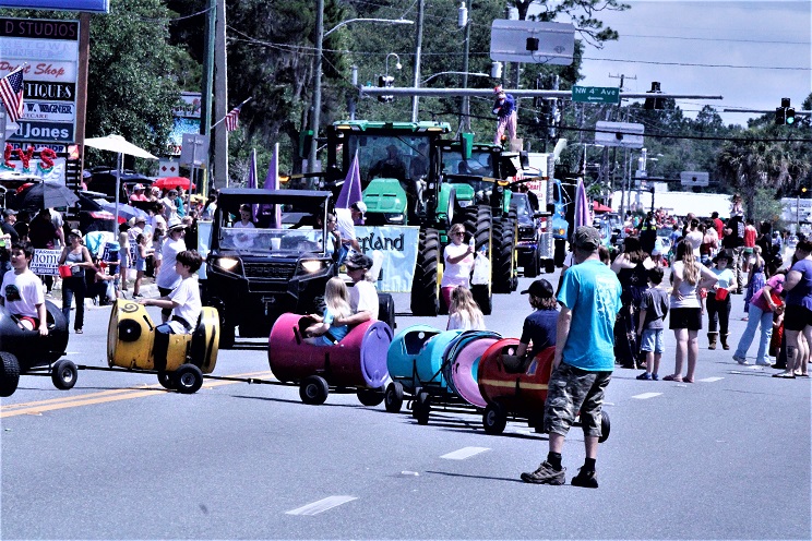 A toy train loaded with young passengers makes its way down the parade route followed by a line of big tractors. The crowd was large.