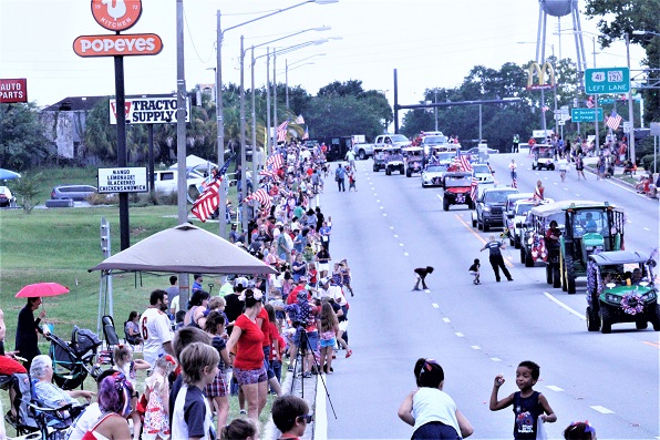 A large crowd decked out in holiday colors watches the parade pass by them on Noble Avenue.