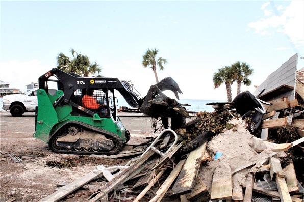 A workman piles debris high on the parking lot of the city marina.