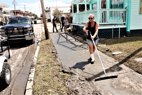 Volunteer Denise Faries scrapes storm mud from a sidewalk in front of Cedar Key Heathcare. Nurse practitioner Tammy Wilks can be seen behind her after concluding an interview with two members of the new media. Big city TV news people were swarming over the island.